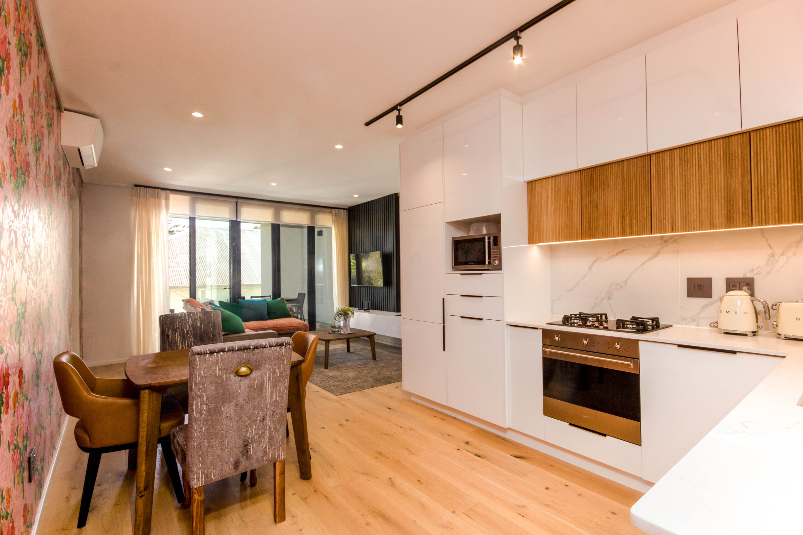 Open-plan kitchen, dining area and lounge with floral wallpaper in the balcony two apartment at Aan de Meul