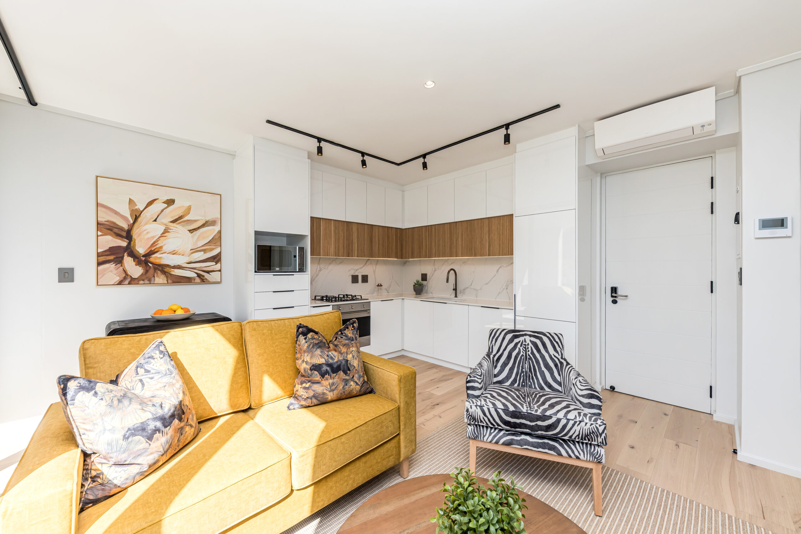 Open-plan lounge with a yellow sofa and adjoining white kitchen in the luxury one apartment at Aan de Meul