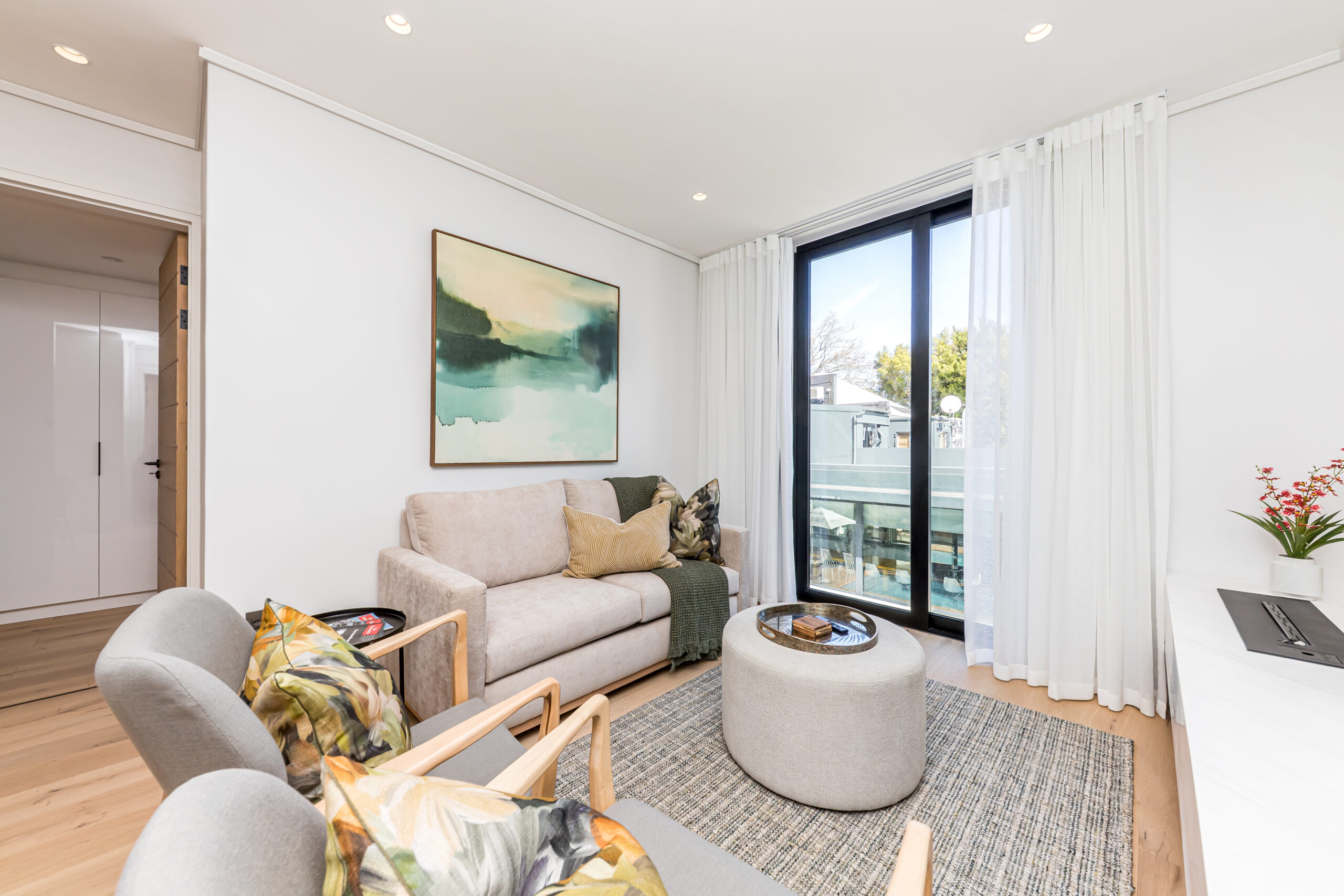 Lounge with a pale sofa and patterned armchairs beside the balcony doors in the luxury two apartment at Aan de Meul