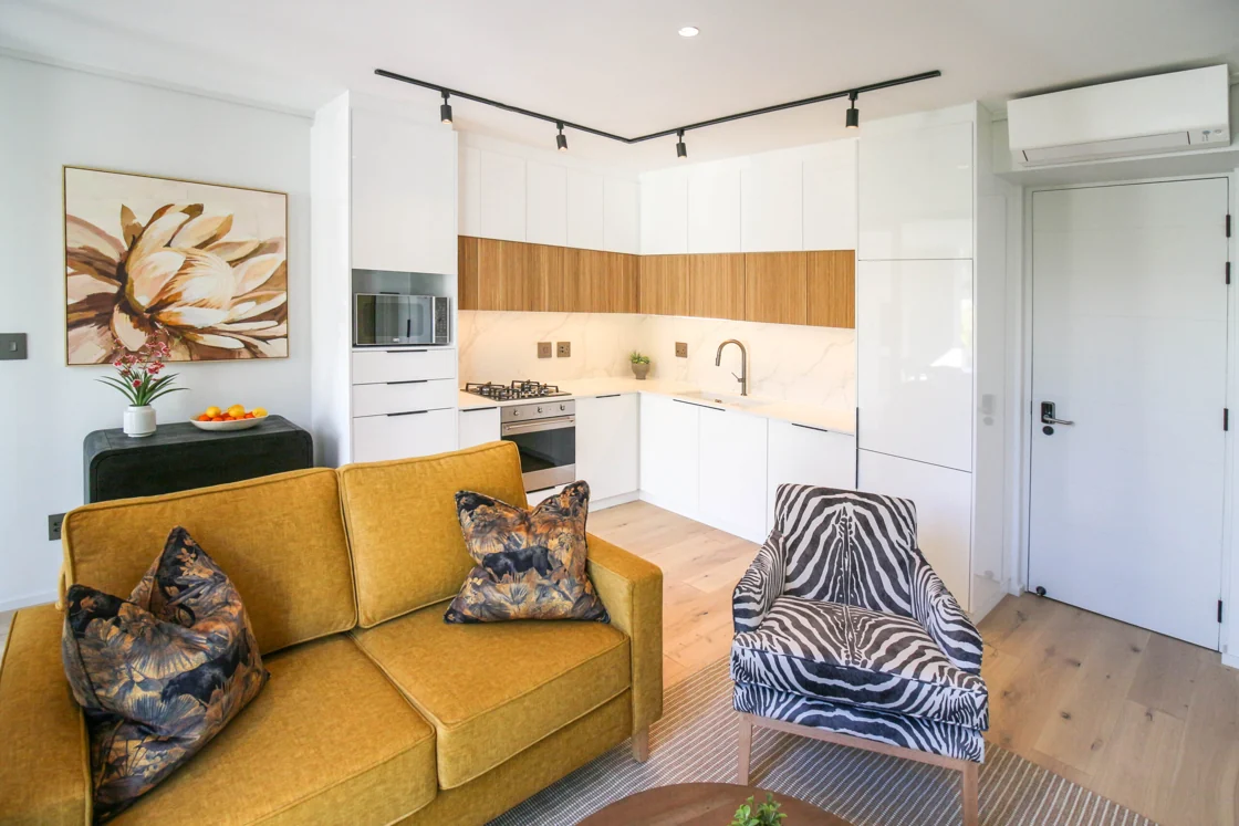 Yellow sofa and zebra-patterned armchair beside the open-plan kitchen in the Luxury One Bedroom apartment at Aan de Meul