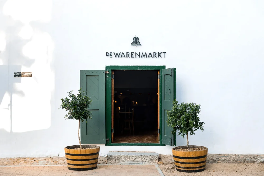 De Warenmarkt entrance with green shutters and trees in wooden planters