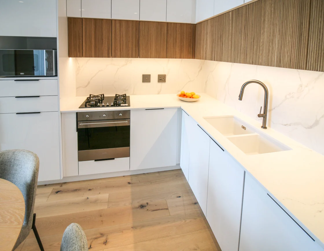 White kitchen with wood-fronted cabinets, oven and gas hob in the Luxury Two Bedroom apartment at Aan de Meul