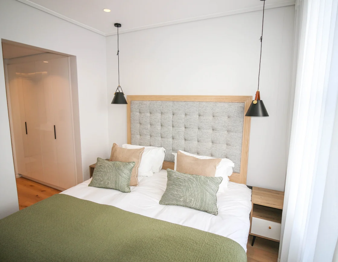 Bedroom with a tall upholstered headboard and green bedding in the Luxury Two Bedroom apartment at Aan de Meul