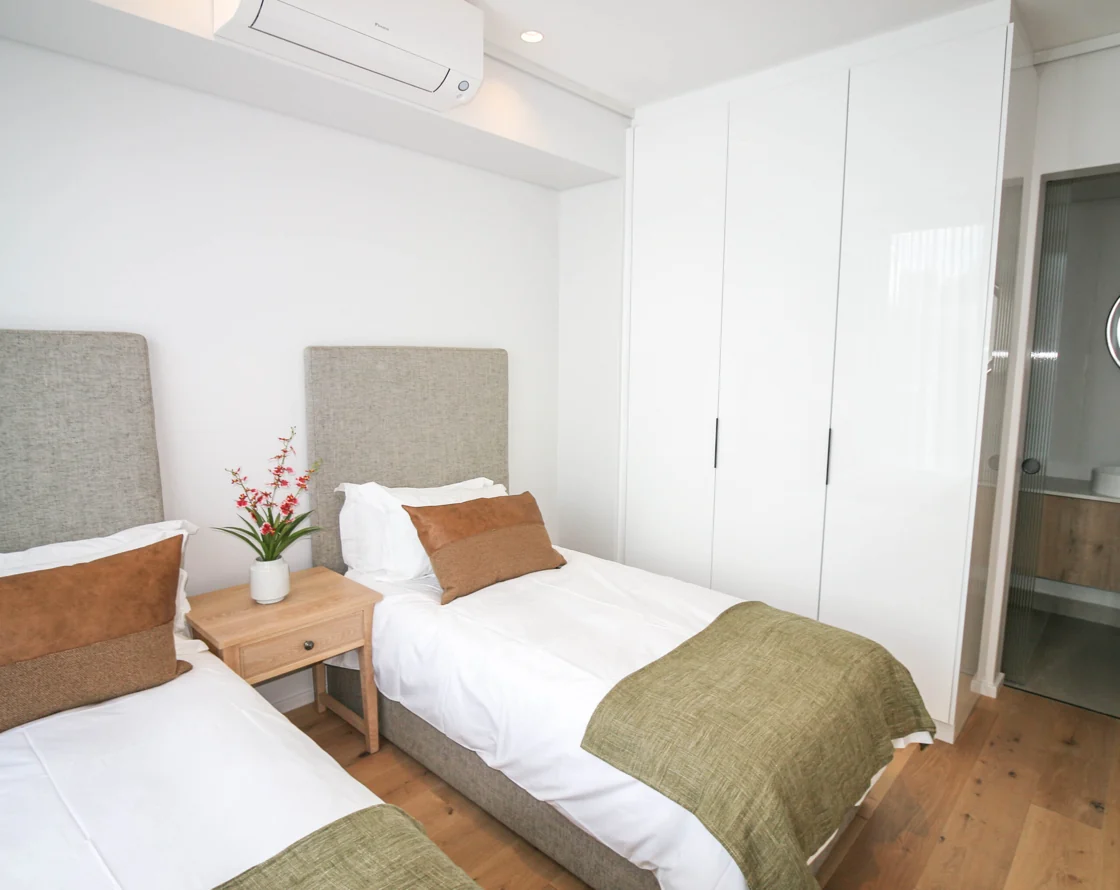 Twin bedroom with upholstered headboards and green bedding in the Luxury Two Bedroom apartment at Aan de Meul