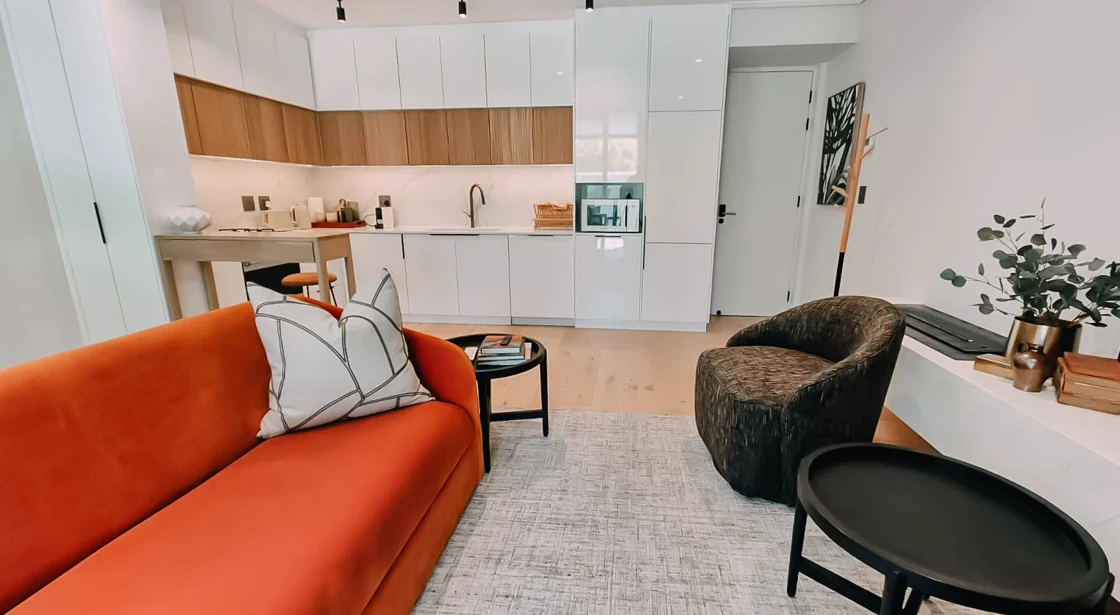 Open-plan lounge with an orange sofa beside the equipped kitchen in the Superior Two-Bedroom Garden apartment at Aan de Meul
